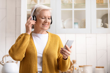 Portrait of happy senior woman listening to music on smartphone