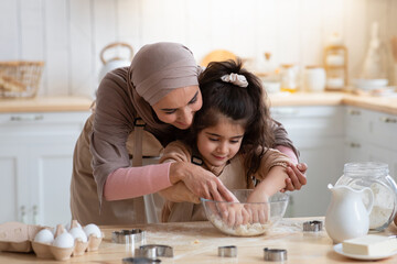 Loving Muslim Mom Teaching Daughter How To Knead Dough In Kitchen