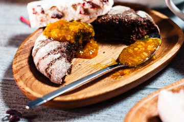 Fototapeta na wymiar Close up choccolate bisquit with spoon of orange jam serving on wooden plate on table