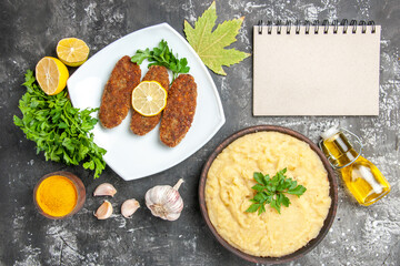 top view mashed potatoes cutlets parsley lemon slices a notebook turmeric on dark background