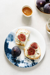 Fototapeta na wymiar Two Sandwich with Ricotta and fresh Figs sprinkled honey on plate on grey concrete background. Simple healthy breakfast