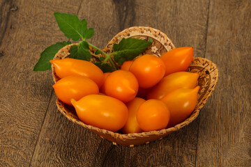 Yellow tomato heap in the wooden bowl