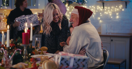 Senior grandparents greeting family with presents on Xmas day
