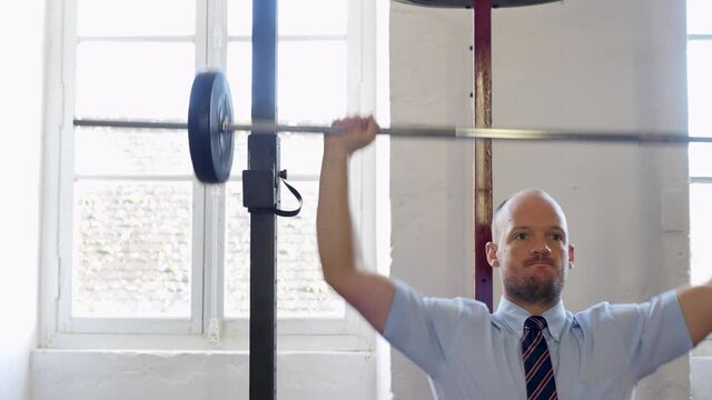 Shoulder military press with barbell in homegym : Man in suit lifting heavy weight in the gym. Businessman doing exercises with barbell in the gym. successful business, revenue growth concept. pushing
