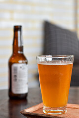 Vertical view, Craft beer in a tall glass with bottle blurred background.