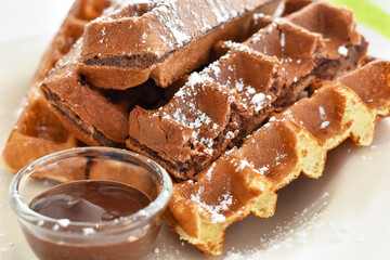 Close-up view, Chocolate waffles with chocolate cream sauce in a glass cup decorated with icing sugar.