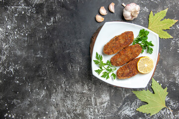 top view cutlets lemon slice parsley on white plate on wooden serving board garlic plane tree leaves on grey background with free space