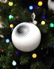 Christmas and New Year. White ball with picture on Christmas green tree