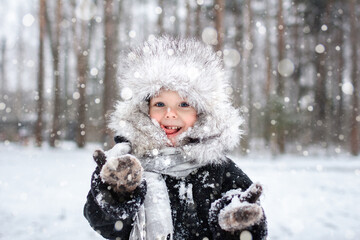 young boy catching snow on his tongue with a snowy background