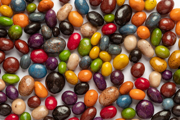 Fototapeta na wymiar A heap of multi-colored glazed raisins on a white background. Rounded candies of different colors and sizes. Healthy and tasty snack.