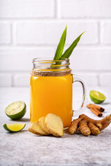 Healthy drink from turmeric and ginger roots and lime in a glass on white background