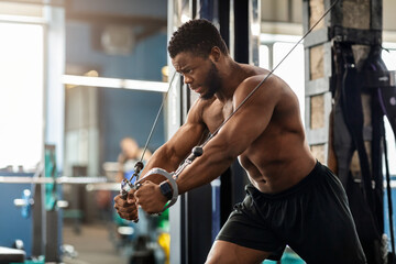Fototapeta na wymiar Young black athlete training triceps on block exerciser in gym