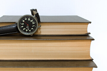 old watch on stack of old yellowed hardback books