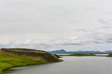Naklejka premium The coastline around the pond Stakholstjorn with pseudo craters - natural monument near Lake Myvatn in Northern Iceland in summer
