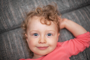 Smiling child lies on the sofa. The girl smiles.