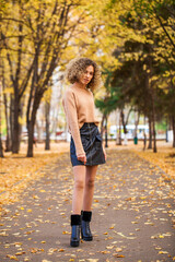 Portrait of a young beautiful girl in beige sweater and black skirt