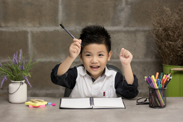 Happy little kid at home making homework. Little child writing with colorful pencils, indoors. Learning and education of kid.