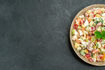 top close view of bowl of vegetable salad on the right side with green on it on dark green background