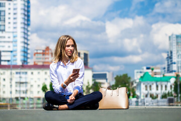 Fototapeta premium Young beautiful business woman sitting in the city square
