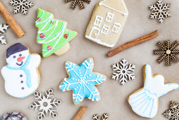 Fototapeta na wymiar Gingerbread painted colored gingerbread cookies and spices and snowflakes on a craft background close-up. Christmas celebration concept. New Year's food.