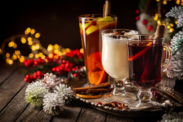 fresh yellow eggnog, grog and fruity red mulled wine with Christmas decoration. Selection of autumn or winter alcoholic hot drinks