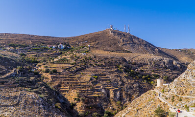 Dry desert landscapes in Syros, Cyclades, Greece with small orthodox church and satellite radio towers on the hill.