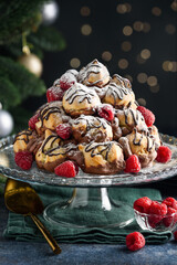 Christmas profiteroles cake with chocolate cream and raspberries. Сroquembouche on a glass cake...