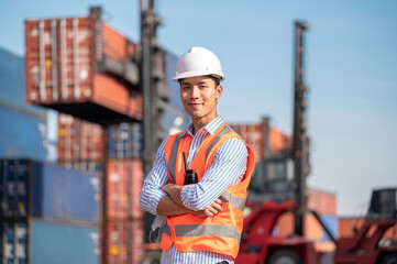 Asian logistics control worker professional wear safety helmets and protect suite working in shipping containerin commercial transport background.