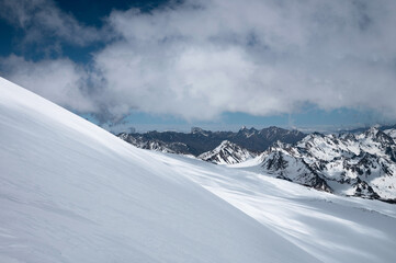 Mountain landscape snowy slope on a sunny day against the backdrop of high mountains