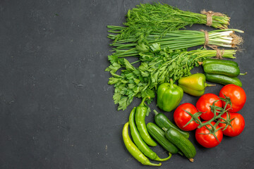 Overhead view of collection of fresh various organic vegetables and greens on dark background