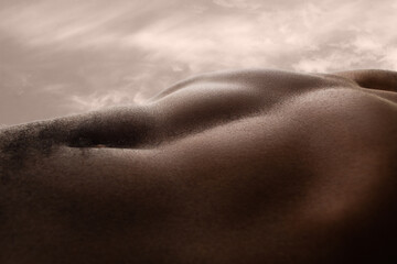 Meadow. Detailed texture of human skin. Close up of young african-american male body surface like landscape with the sky on background. Skincare, bodycare, healthcare, inspiration, fantasy artwork.