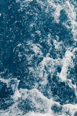 Bubble sea water surface background close-up. Rapid blue splashing water texture with white foam. Caribbean lifestyle themes