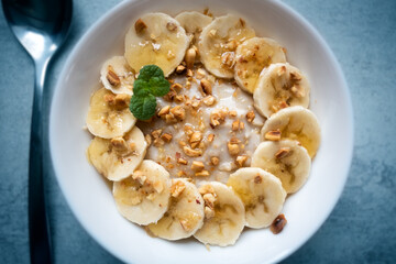 Oatmeal with banana, nuts and honey in white bowl closep. Natural health dieting food