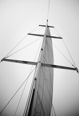 Sails of a sailing yacht in the wind sailing on the sea. Looking up at sail boat mast and rigging. In monochrome.