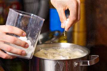 adding salt to a pot of boiling dumplings. Boiled dumplings in a pan