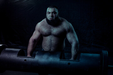 Fototapeta na wymiar a bearded athlete with large muscles holds a heavy iron projectile for power extreme