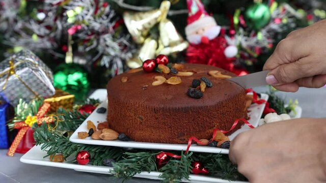 Indian Christmas celebration 4K slow motion video , footage. Woman cutting homemade Christmas plum cake India Kerala. Fruitcake of dried fruit, nuts, spices , rum New Year party, Easter, Christmas Eve