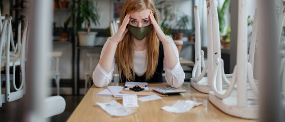 Frustrated manager sitting at table in closed cafe, small business lockdown due to coronavirus.