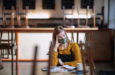 Frustrated owner sitting at table in closed cafe, small business lockdown due to coronavirus.