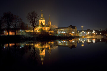 Fototapeta na wymiar Seligenstadt bei Nacht mit dem Spiegelbild der Basilika und der Häuser im Main