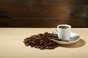 white coffee cup and coffee beans are on a wooden background. 