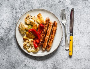 Turkey sausage and baked vegetables on a gray background, top view