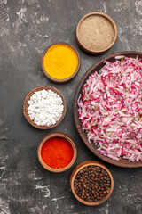 Vertical view of delicious vegetable salad with various ingredients in a brown bowl different spices on dark background