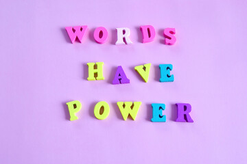 lettering Words have power on a pink background composed of multicolored wooden letters in the abc alphabet block, copy space for your ad text. The concept of learning English.