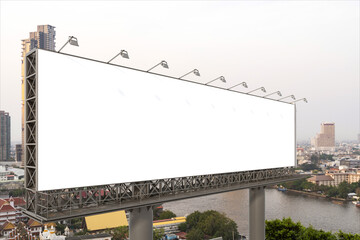 Obraz premium Blank white road billboard with Bangkok cityscape background at day time. Street advertising poster, mock up, 3D rendering. Side view. The concept of marketing communication to promote or sell idea.