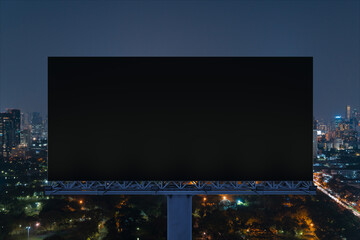 Blank black road billboard with Bangkok cityscape background at night time. Street advertising...