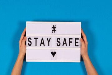 Hands holding lightbox with message Stay Safe on light blue background. isolated. Healthcare,...
