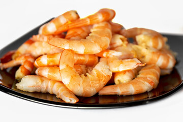 Peeled shrimp on black plate on white background
