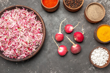 Close up view of vegetable salad with various ingredients in a brown bowl different spices leaf and red radishes on dark background