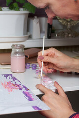 The woman paints by numbers. Acrylic paints on canvas. Nearby are paint cans and other accessories.